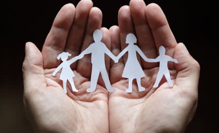 hands holding a paper cutout of family