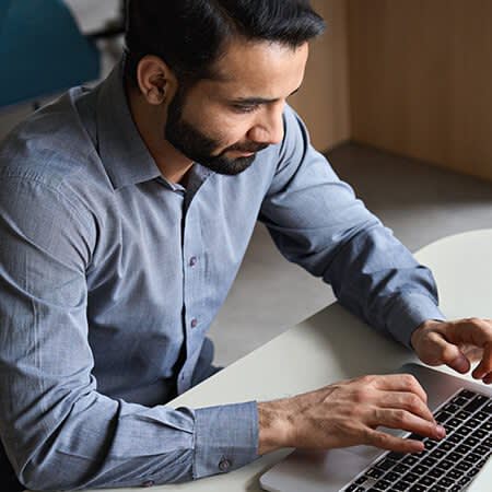Man typing at computer with coffee nearby