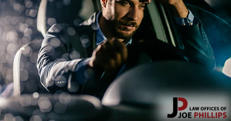 Man driving with one hand on the wheel and one hand on his head