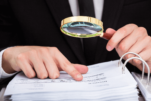 Magnifying glass looking at stack of paper