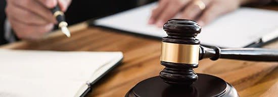 Judge signing documents with a gavel next to them