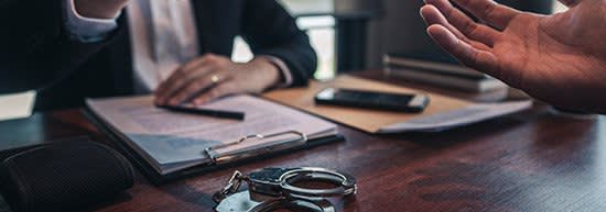 client talking to lawyer with handcuffs in foreground