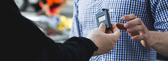 Policeman Giving a Breathalyzer to A Driver