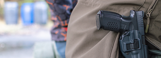 A person with a holstered gun sits on a bench