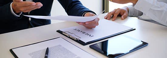 2 men discussing insurance claim with documents in front of them