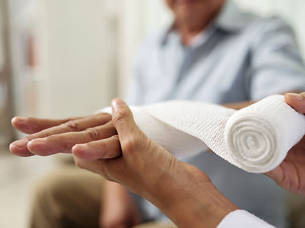 Hand being bandaged by nurse