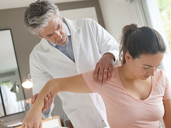 Physical therapist assisting a woman with an arm injury