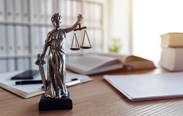 Lady justice holding scales sitting on a desk