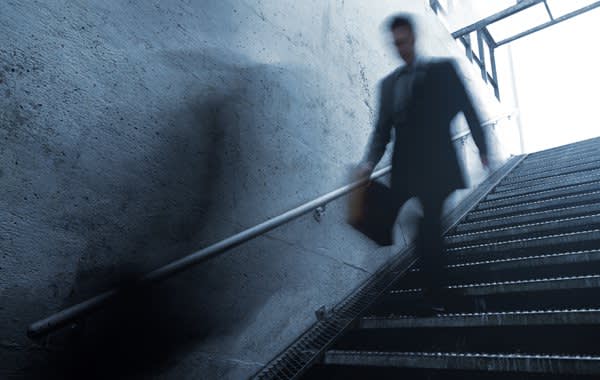 blurred man in suit walking down subway stairs