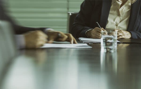 Two Men Writing on Paper at a Conference Table