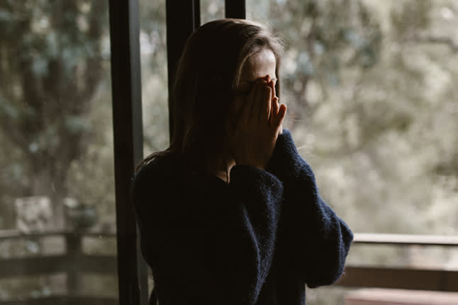 Upset woman with hands folded over face
