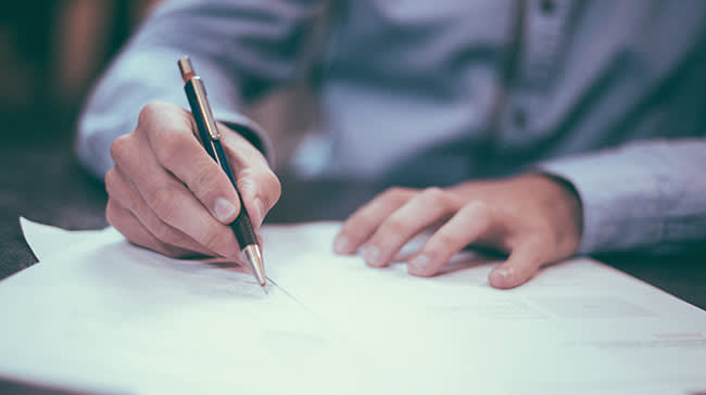 Man with a pen in his hand writing on papers