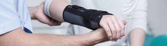 Close up of a person's wrist in a black brace being helped by a man