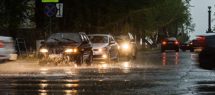 Three cars driving close together in a line while its raining