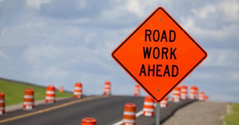 Road work ahead sign on road with cones along it