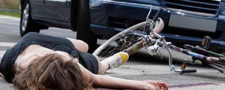 woman lying on street next to bicycle and car