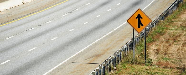 Merge road sign on the side of an empty road