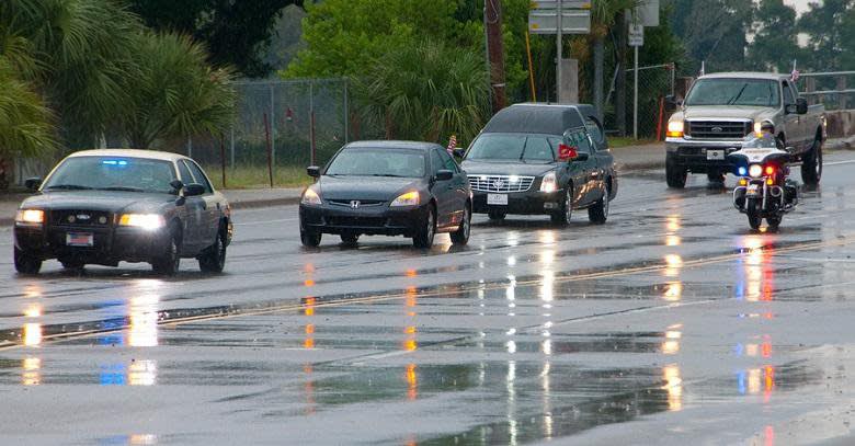 Police cars and motorcycle driving on a wet road