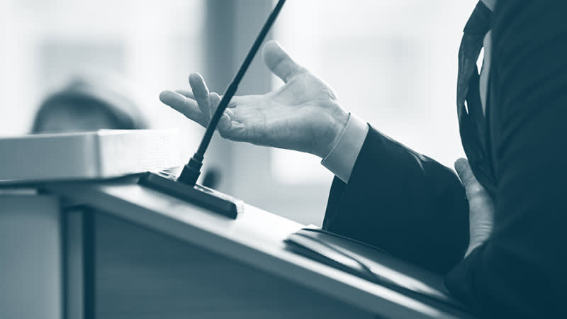 Man speaking at a podium in a courtroom