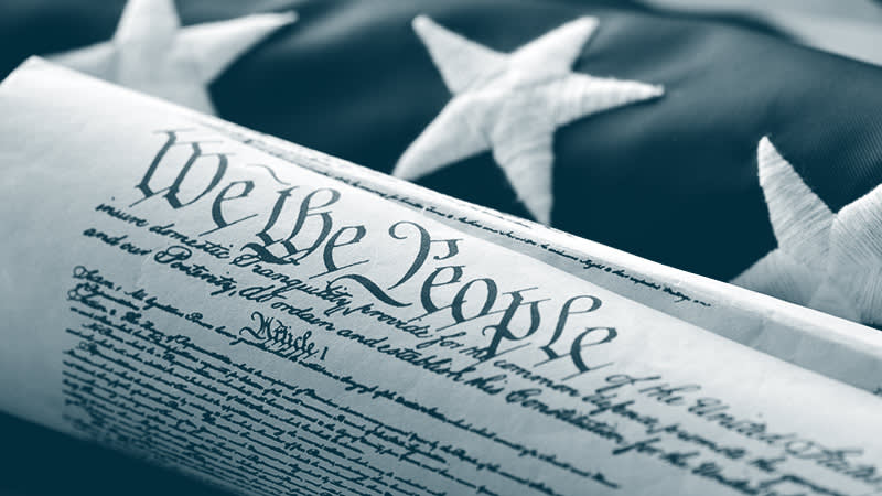 Constitution of the United States rolled up on top of an American flag