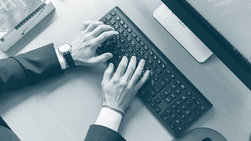Man in suit typing on a computer keyboard
