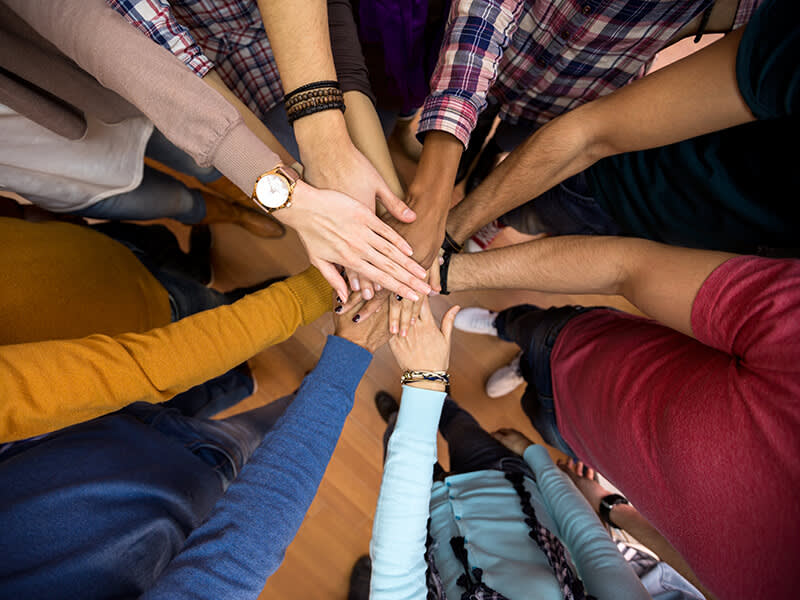 A group of people with their hands in together symbolizing teamwork