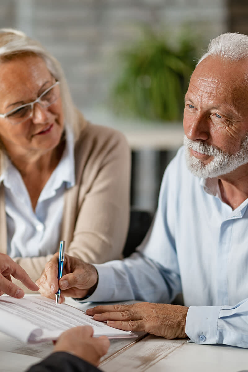 Senior couple signing a contract while having a meeting with insurance agent in the office.