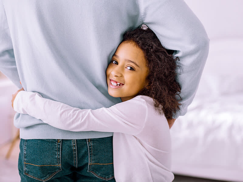 Little girl hugging her father while smiling