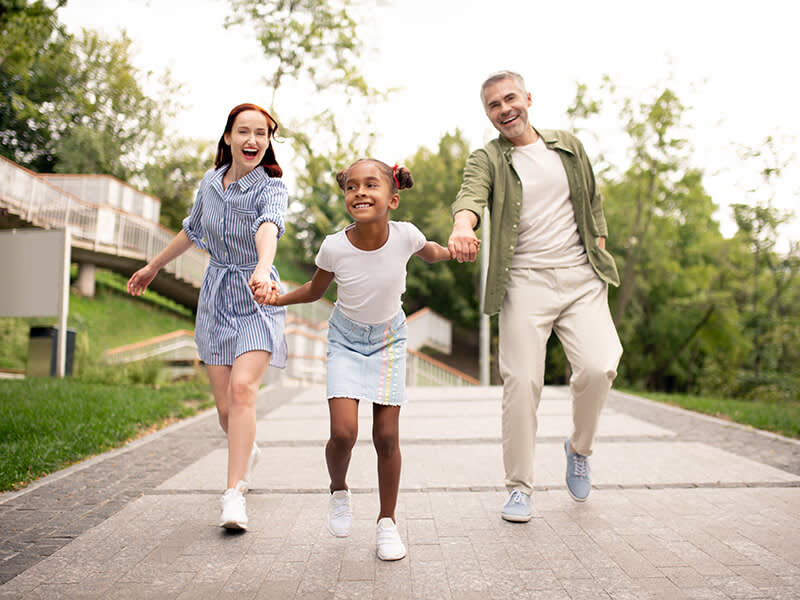 Two parents playing with a young girl on a sidewalk