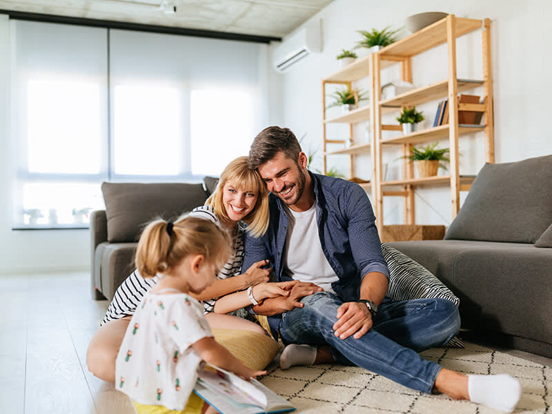 Happy parents watching their daughter play with a book