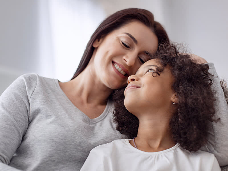Woman smiling at a little girl while they sit together on the couch