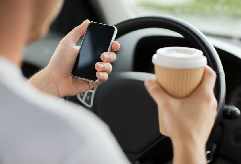 Man Driving Holding Coffee and Phone