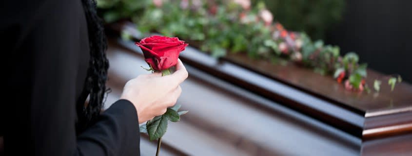 Woman Standing in front of a Coffin Holding Rose