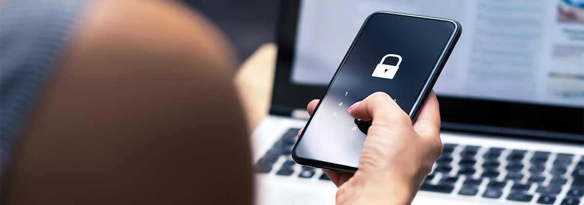Person holding phone in front of laptop with image of padlock