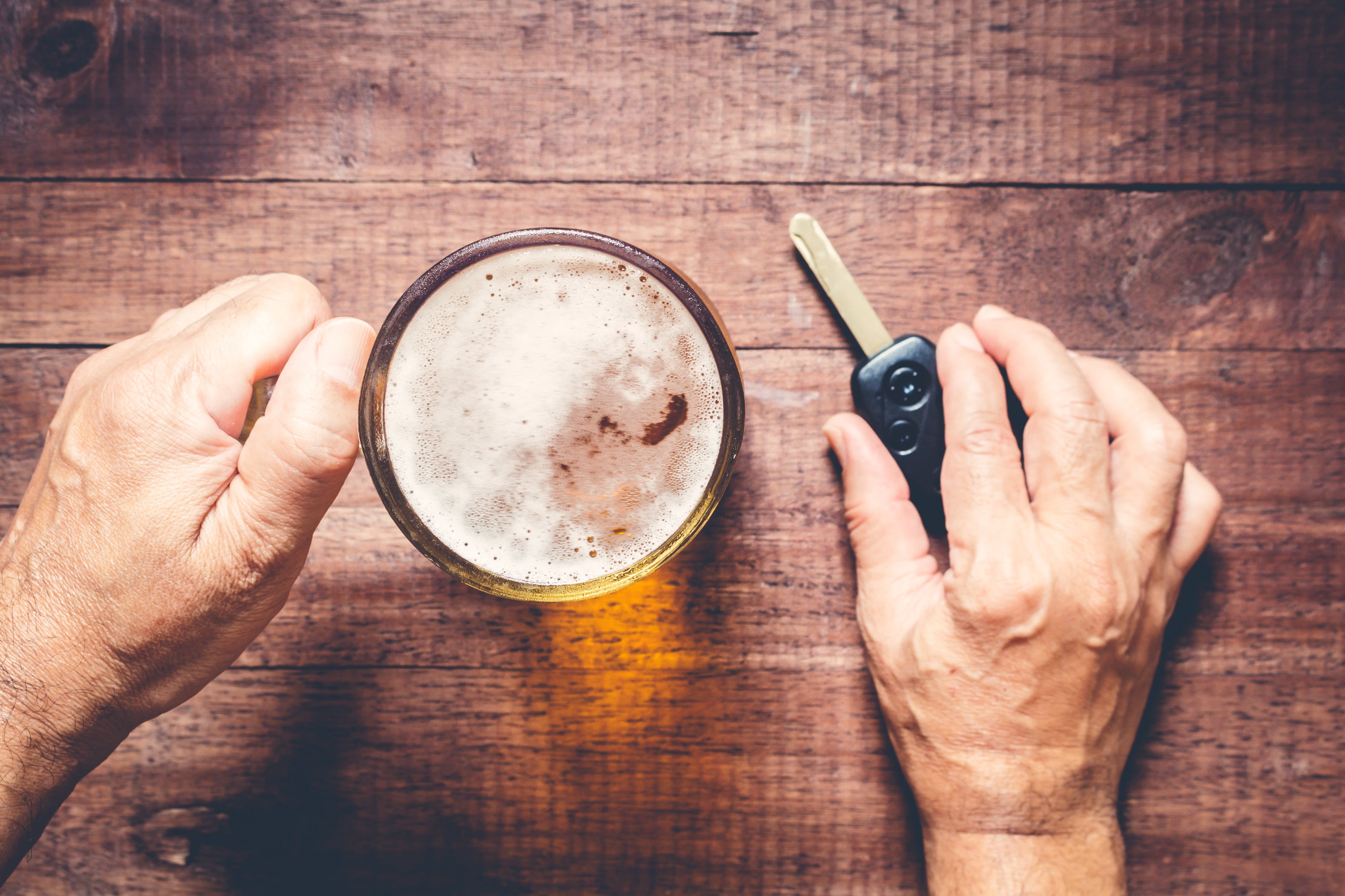A man holding a beer in one hand and car keys in the other