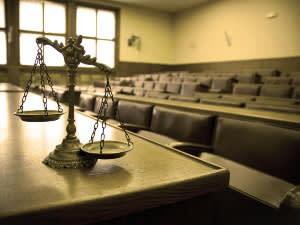 Sepia-toned image of scales of justice in empty courtroom