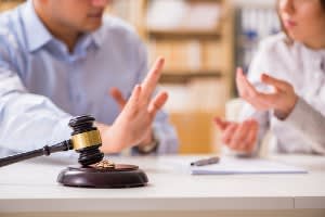 A couple having a discussion near a gavel and two wedding rings