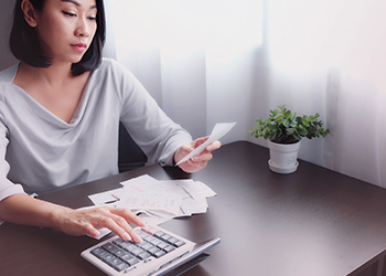 A woman adds up receipts on a large calculator