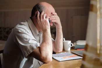 Man on the phone with hand on head