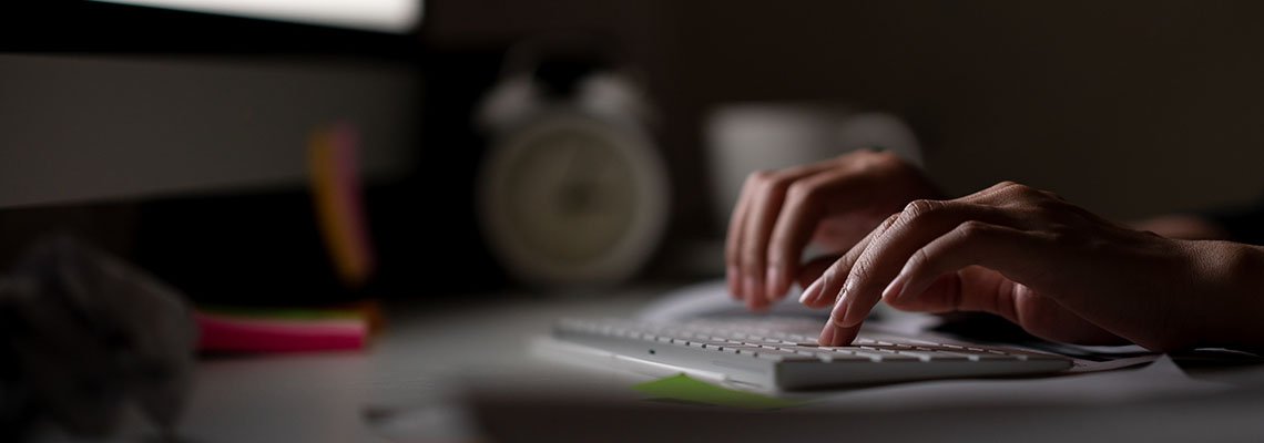 Person typing on a keyboard in a dark room