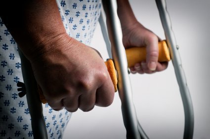 person in a hospital gown using crutches