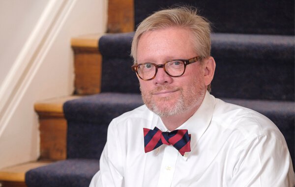 E Gordon Peters sitting on a staircase looking at camera