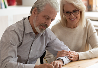 Happy older family couple husband and wife sign legal paper