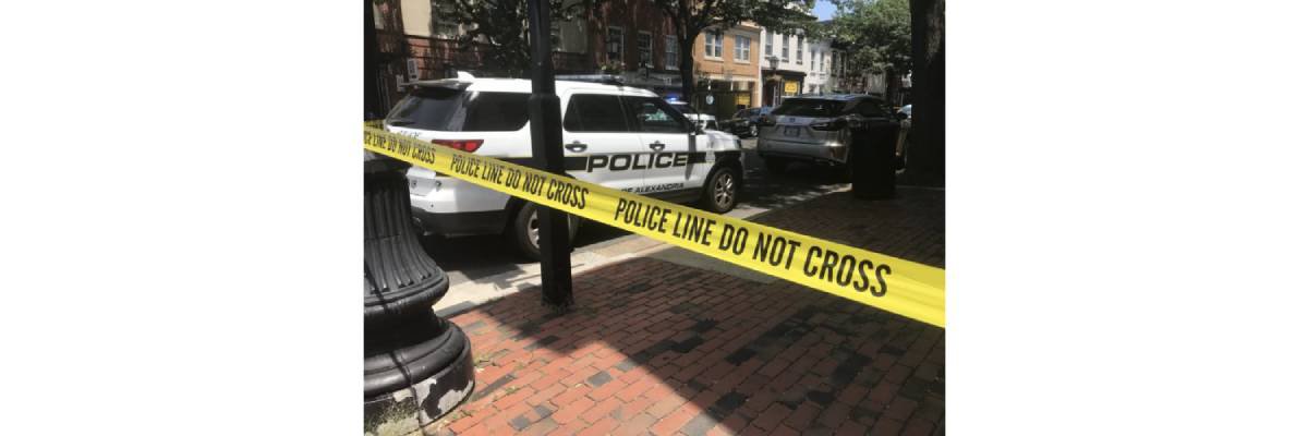 Police Tape over sidewalk with a parked cop car nearby