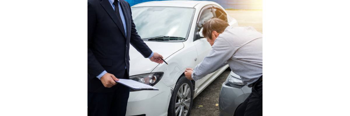 Man with an insurance adjuster examining car damage