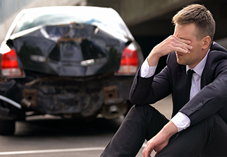 Desperate man sitting asphalt on crashed car background, automobile accident