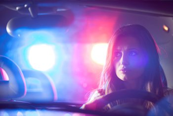 Woman in car with police lights behind