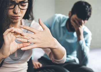 sad woman removing marriage ring with sad man