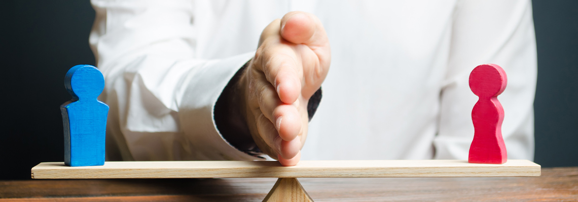 Hand dividing two wood figures of a man and woman