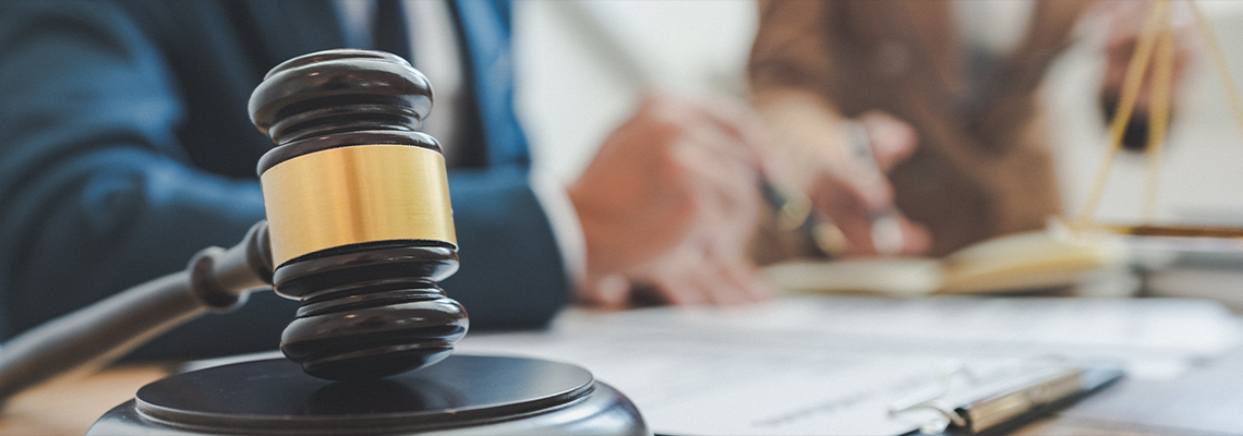 Two people sitting at desk with a gavel and paperwork